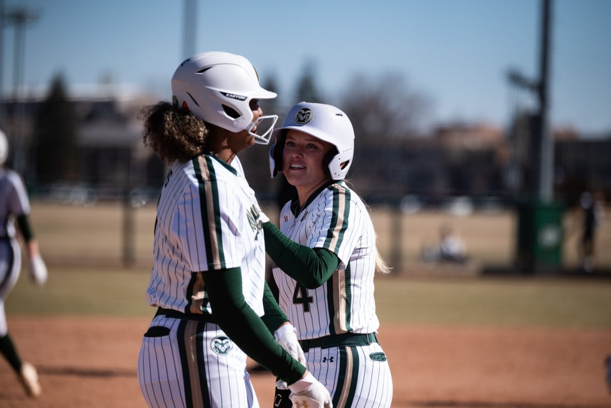 Jailey Wilson (10) and Molly Gates (4) talk before going up to bat against Iowa State.