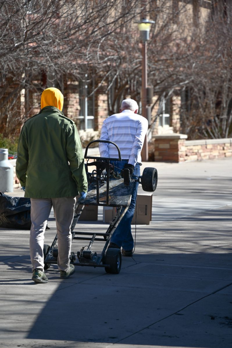 A student and his professor wheel away the chassis of the go kart that caught fire in the engineering building last week. Cleanup of all of the ruined and unusable projects happened outside of the Engineering Building by the LSC Plaza the morning of March 5, 2024 