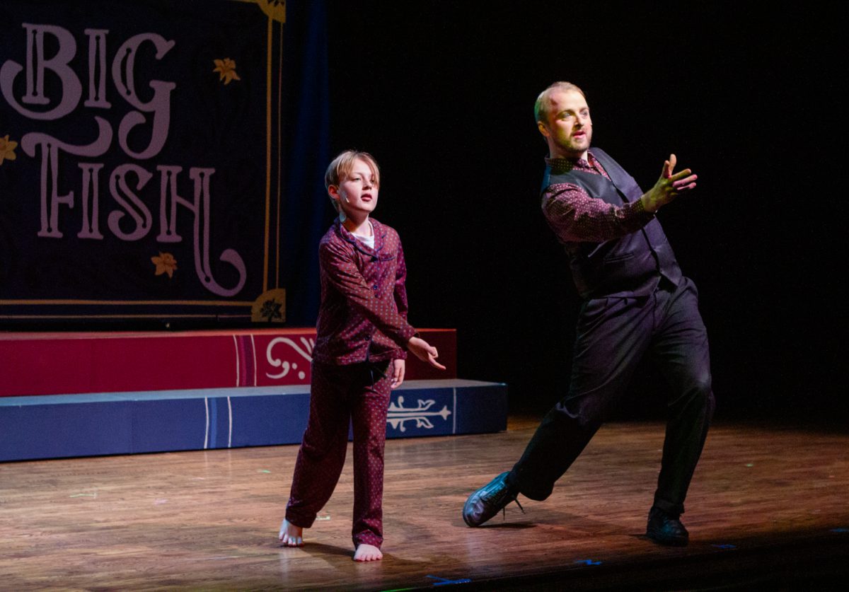 A little boy and a man perform on stage.