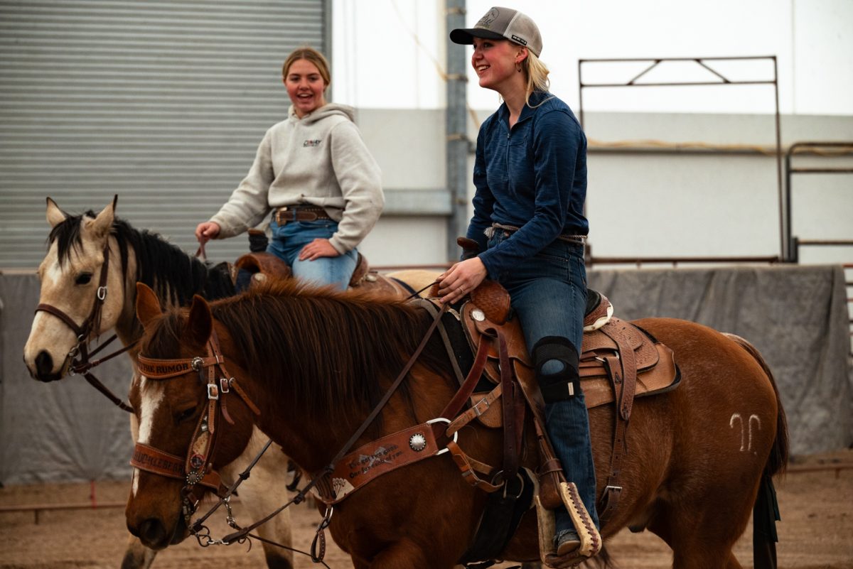 Sadie Johnson and Mckinlee May talk while warming up their horses at a Colorado State University rodeo team practice in Nuun, Colorado.