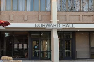 The front of a building with the words, Durward Hall, written above the metal and glass entrance doors.