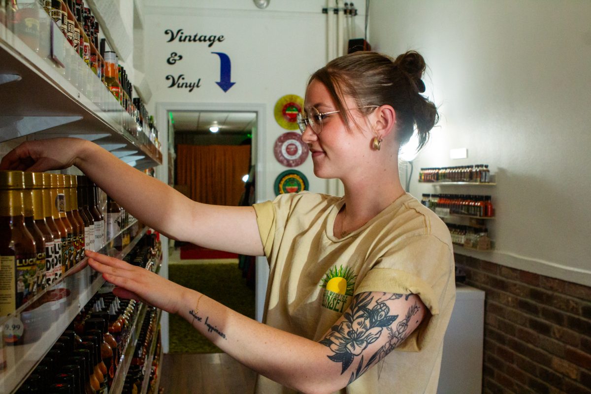 A woman restocks hot sauce on a shelf.