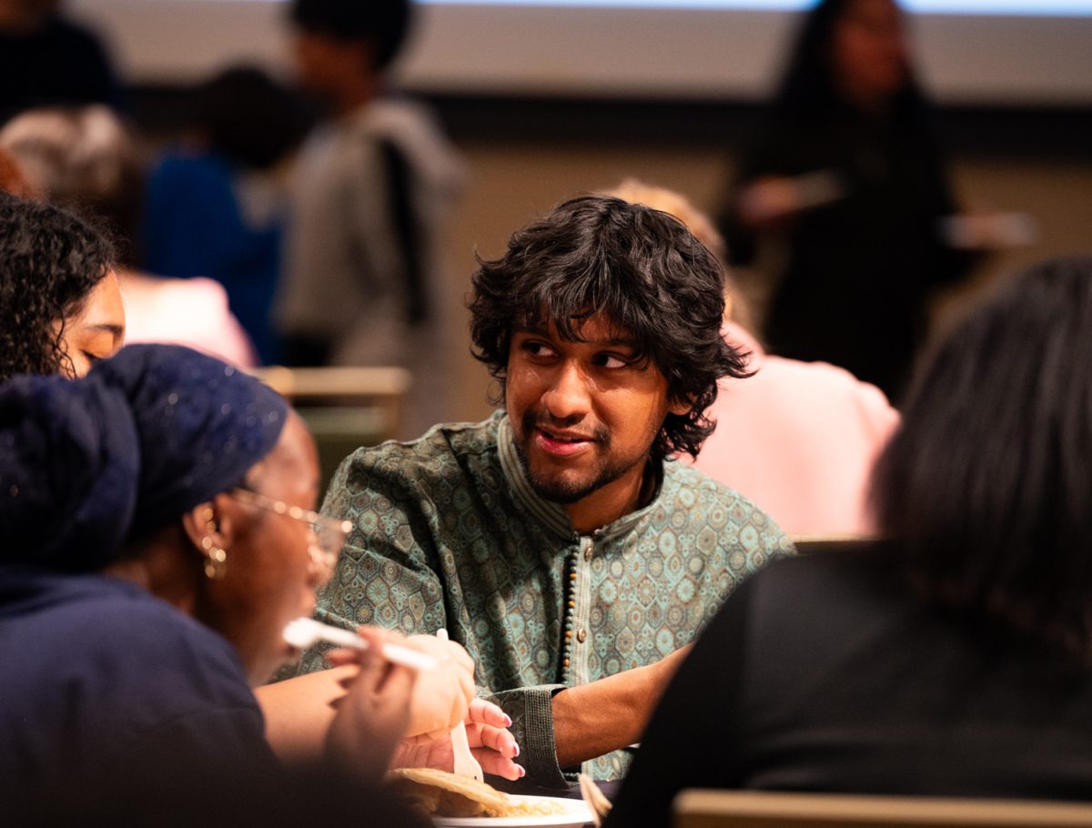 Faraac Bukhari, a member of the Asian Pacific American Cultural Center, talks and eats with friends at the Ramadan Iftar Dinner Event.