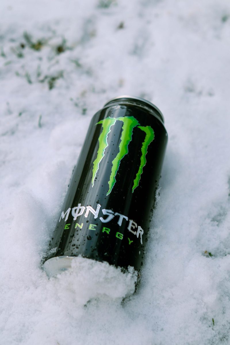 A Coca-Cola Monster Energy drink in the snow with water droplets scattered on the can. March 26.