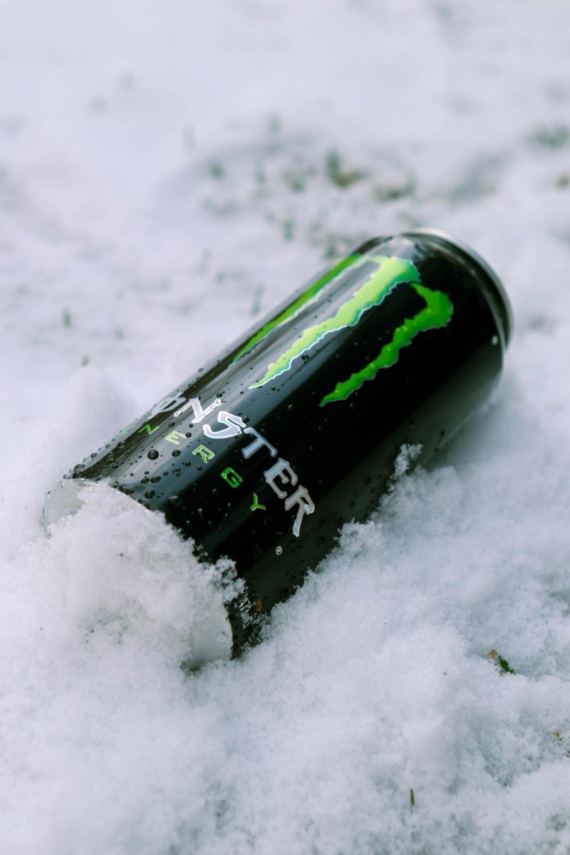 The right side of a Coca-Cola Monster Energy drink in the snow with water droplets scattered on the can. March 26.