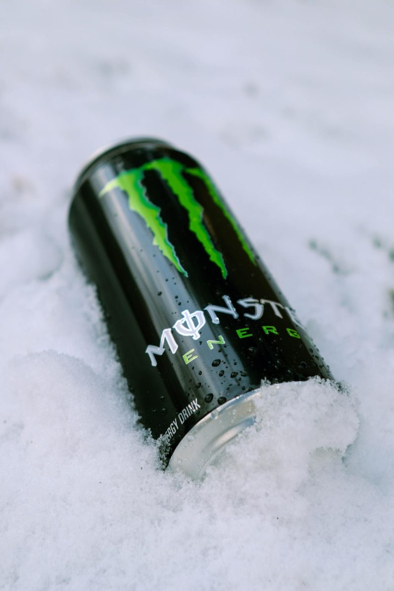 The left side of a Coca-Cola Monster Energy drink in the snow with water droplets scattered around the can. March 26.