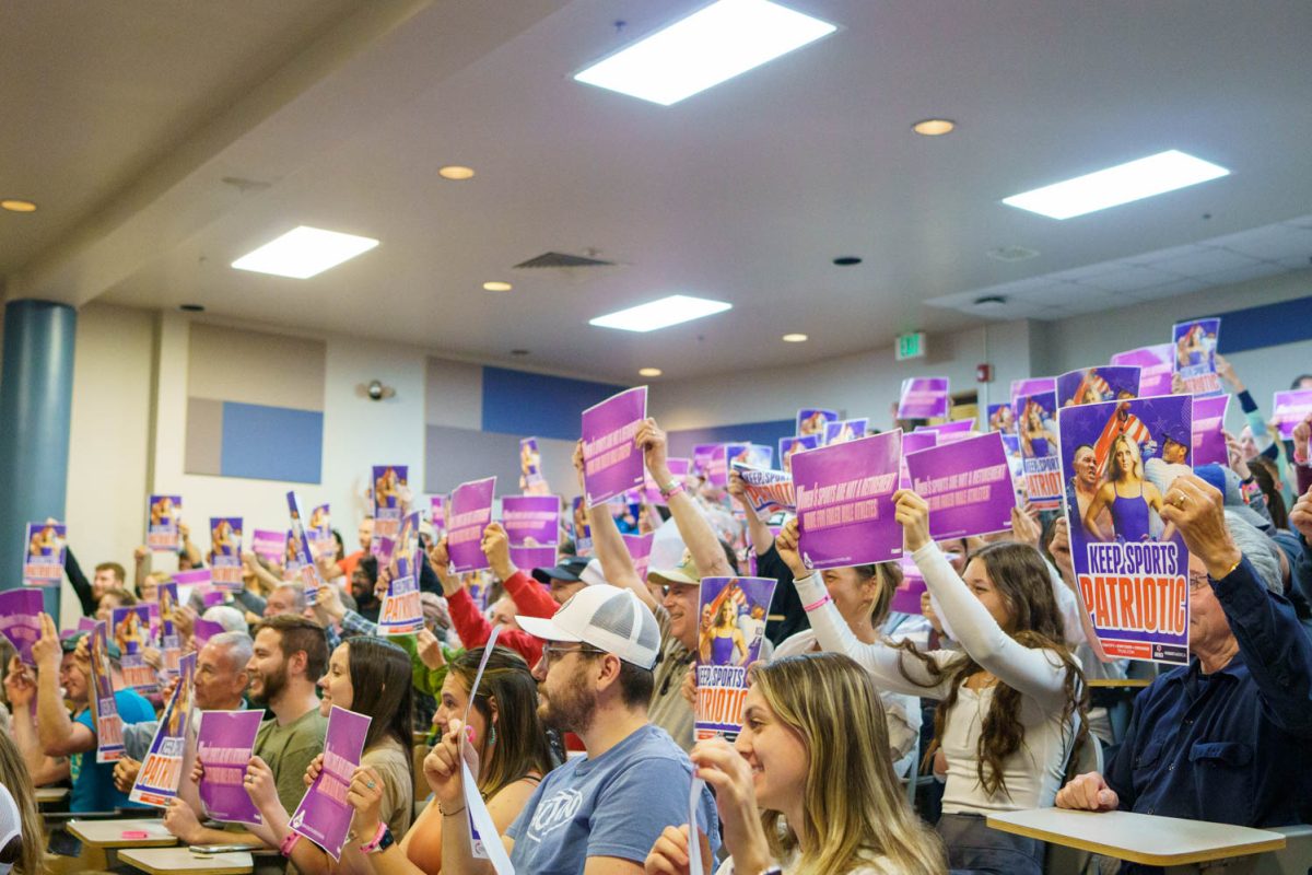 Attendees at the Riley Gaines talk, hosted by Colorado State Universitys student chapter of Turning Point USA and The Riley Gaines Center at the Leadership Institute, hold up posters and signs for a photo April 3. Defend your daughters; defend your kids, Gaines said.