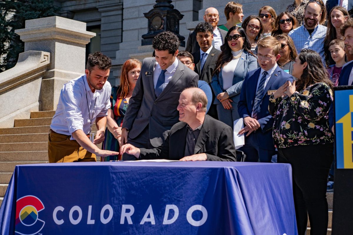 Gov. Jared Polis signs HB24-1007 on the west steps of the Colorado state Capitol building April 15. The opportunity for people to officially be on the lease gives them protections, Polis said during the signing ceremony.