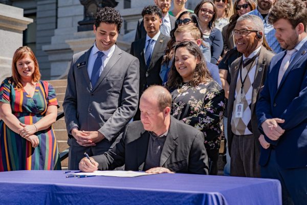 Gov. Jared Polis signs HB24-1007 on the west steps of the Colorado state Capitol building April 15. The opportunity for people to officially be on the lease gives them protections, Polis said during the signing ceremony.