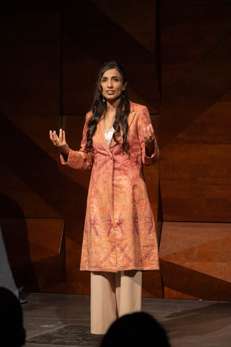 A woman speaks animatedly on a stage.