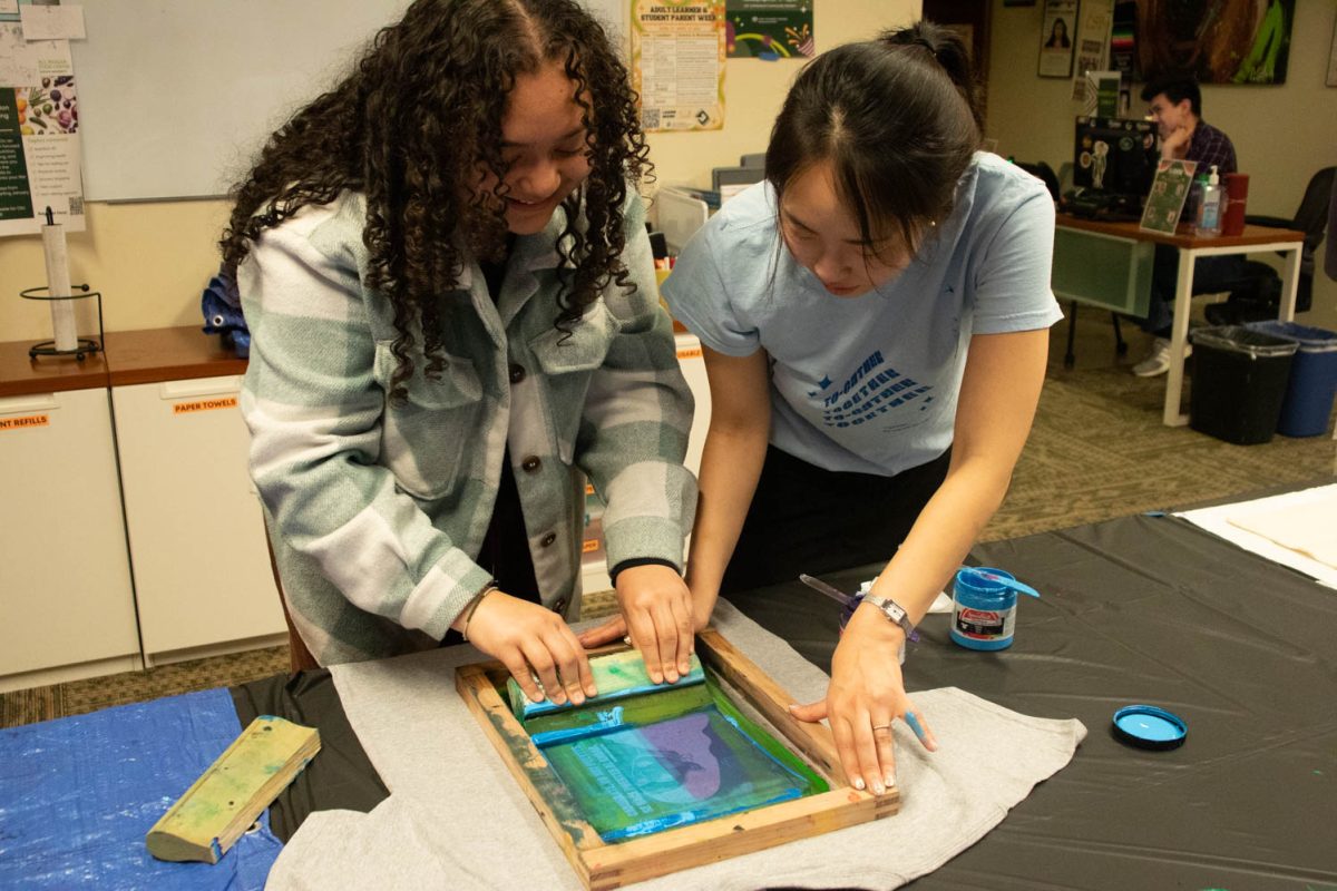 Angelita Chavez and Seojung Lee work together to print a design on a t-shirt during the Love Women of Color: Celebrating Empowerment Through Art screen printing workshop April 18.