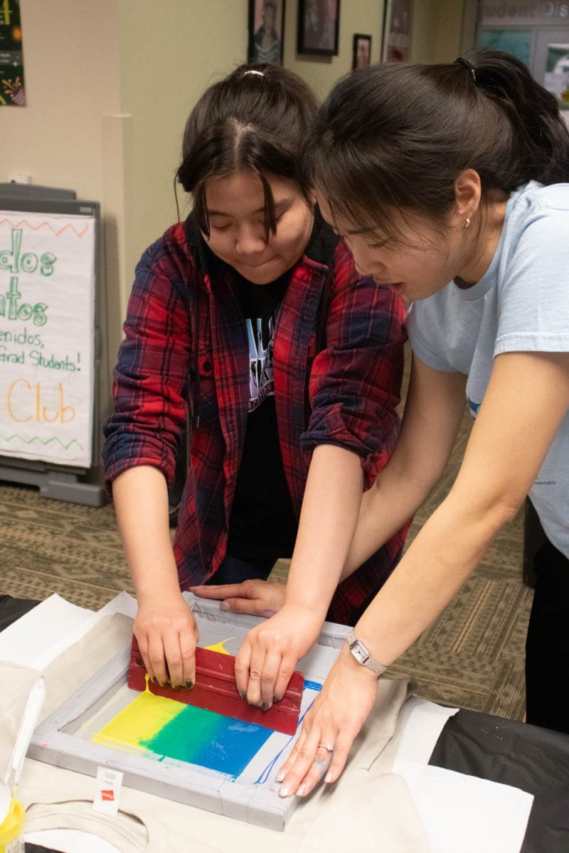 Seojung Lee helps a participant during the Love Women of Color: Celebrating Empowerment Through Art screen printing workshop April 18.