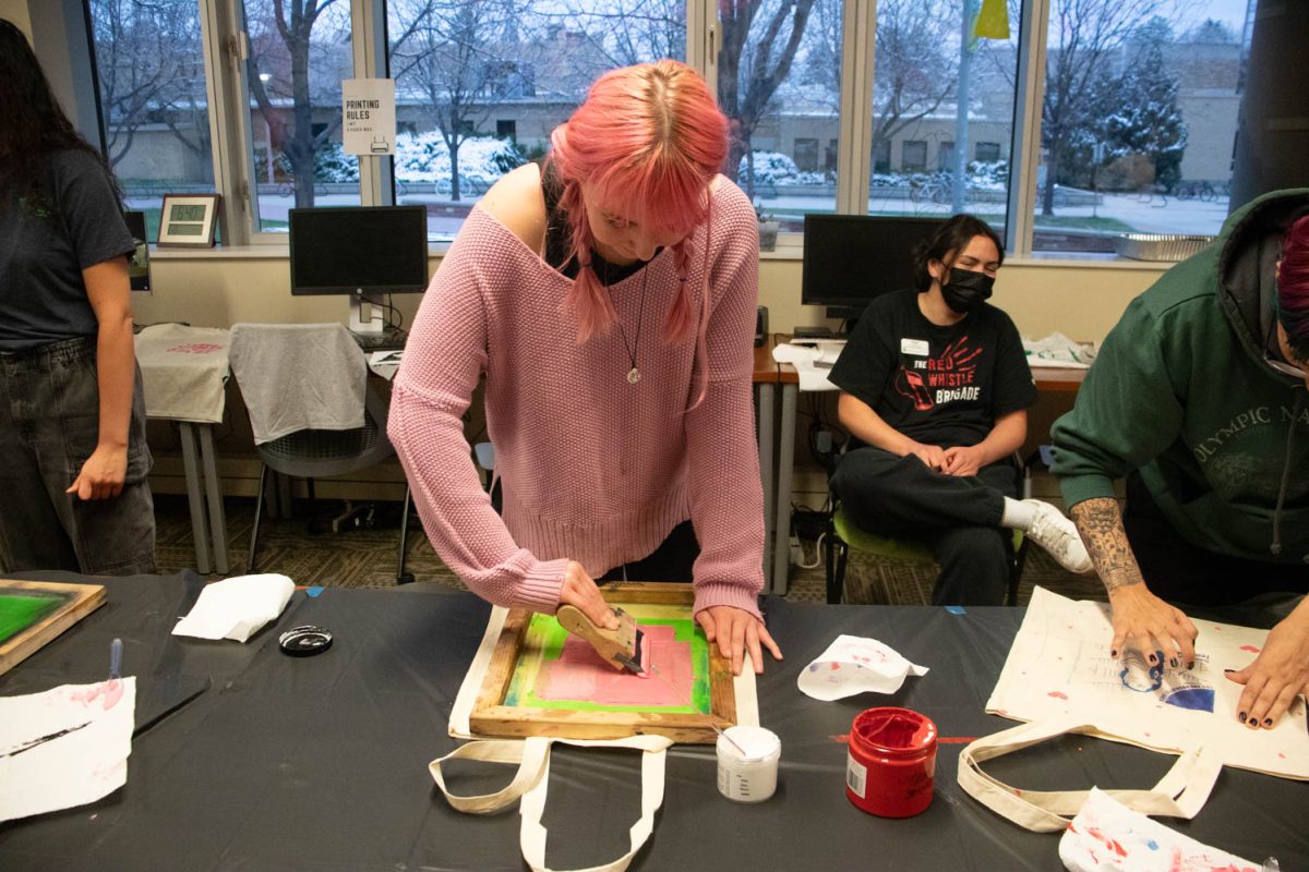 Kitty Bagwell swipes paint across a silk screen during the Love Women of Color: Celebrating Empowerment Through Art screen printing workshop April 18.
