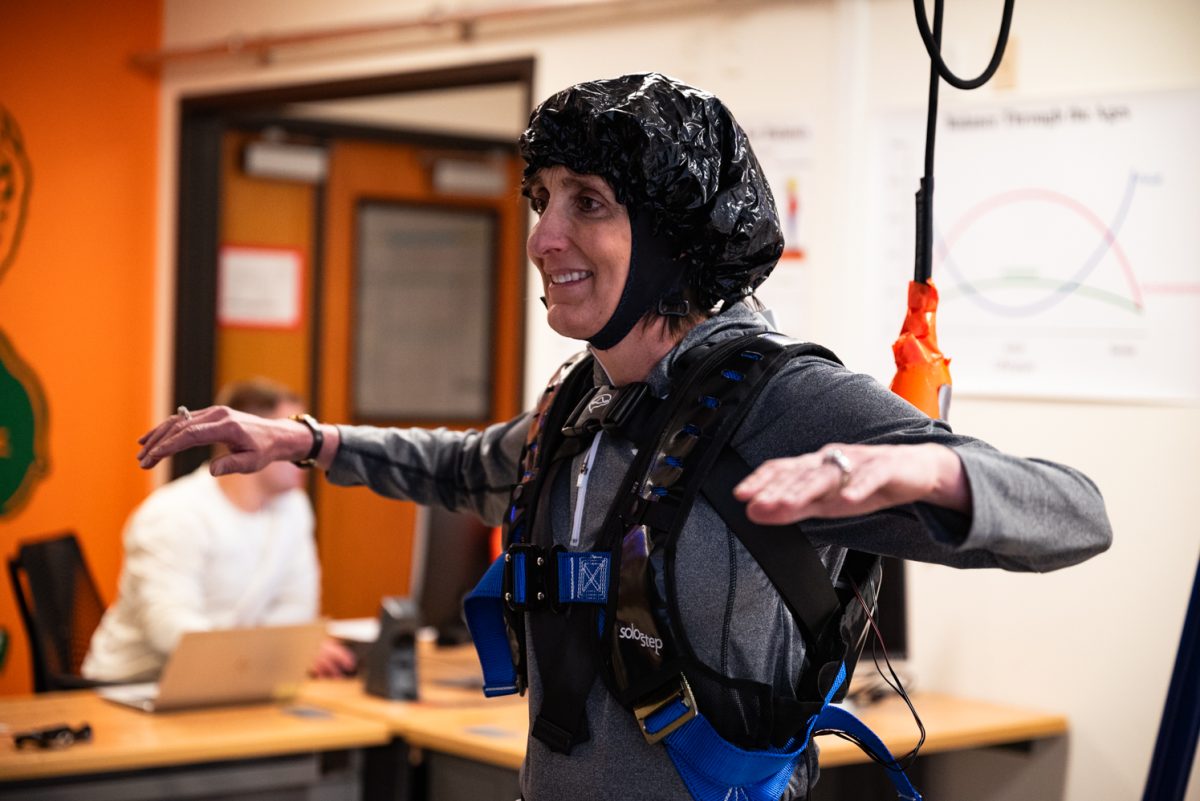 Study participant Jonna Patton gets ready to walk on a split-belt treadmill March 20. For a few moments, Patton was instructed to hold her arms out and stay still so the sensors could process her resting brain activity before she started to walk.