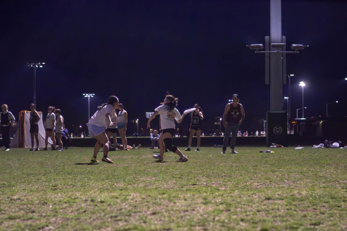 A member of the Colorado State University Womxn's Ultimate frisbee club team  "Hell's Belles" throws the frisbee around a player at their practice. Apr. 4.