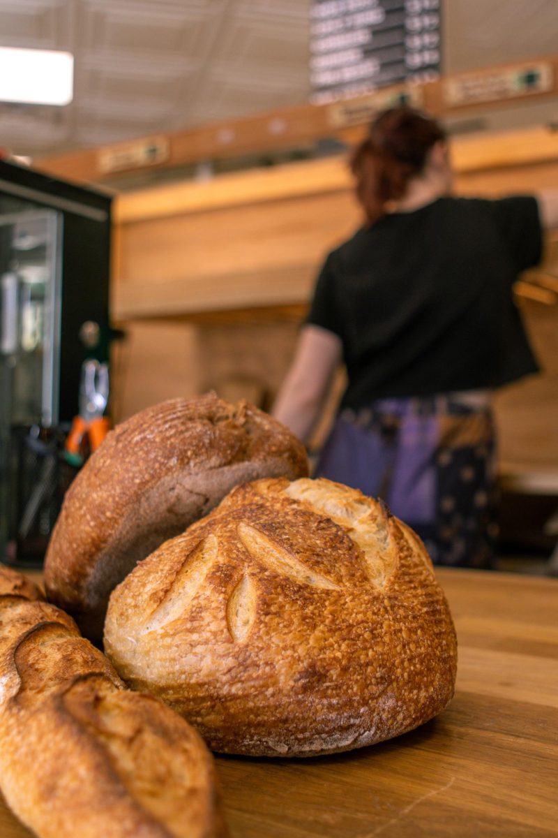 Freshly baked loaves and a baguette are shown stacked on the counter while a worker packs away the leftover bread which is donated after The Bread Chic closes every day. Apr. 8.