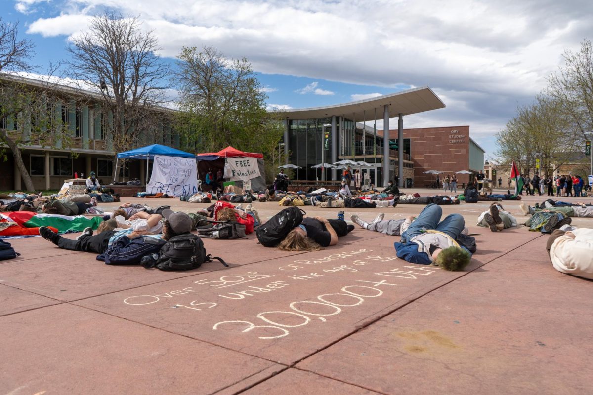 Several protesters lie on the ground around a chalk message, which ends with 30,000 plus deaths written in large letters.