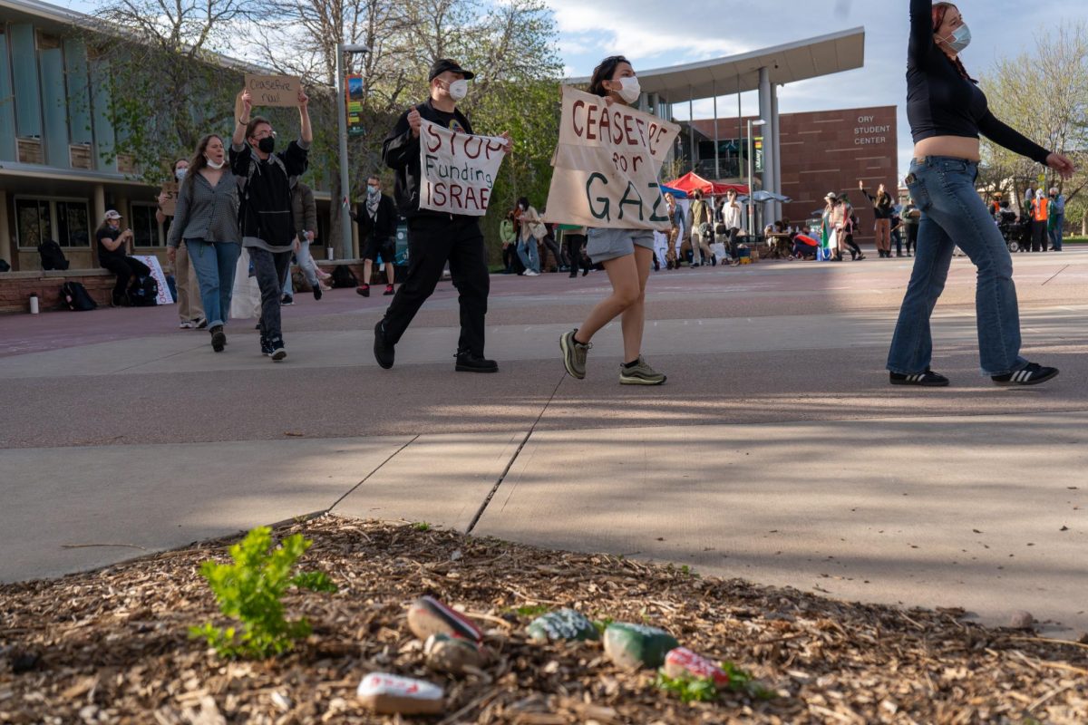 A line of protesters walks in front of the Lory Student Center. Two signs held by protesters read, Stop funding Israel, and, Ceasefire for Gaza.