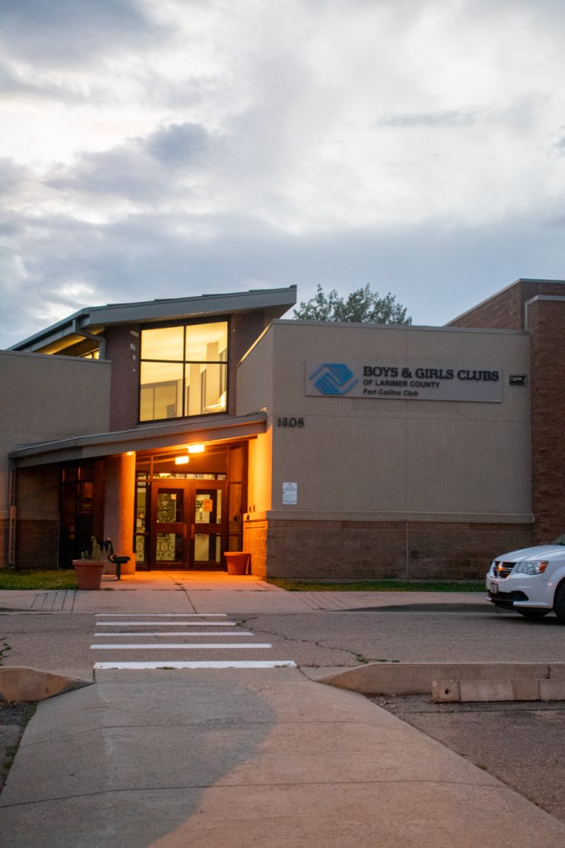 The exterior and parking lot of a building with a white car parked on the right. A sign on the building says "Boys and Girls Club of Larmier County Fort Collins Club.