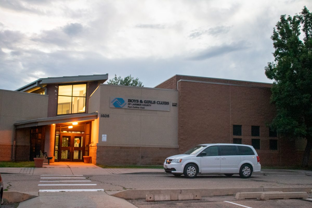 The exterior and parking lot of a building with a white car parked on the right. A sign on the building says "Boys and Girls Club of Larmier County Fort Collins Club.