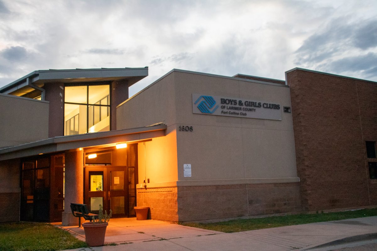 The exterior and parking lot of a building with a white car parked on the right. A sign on the building says "Boys and Girls Club of Larmier County Fort Collins Club.