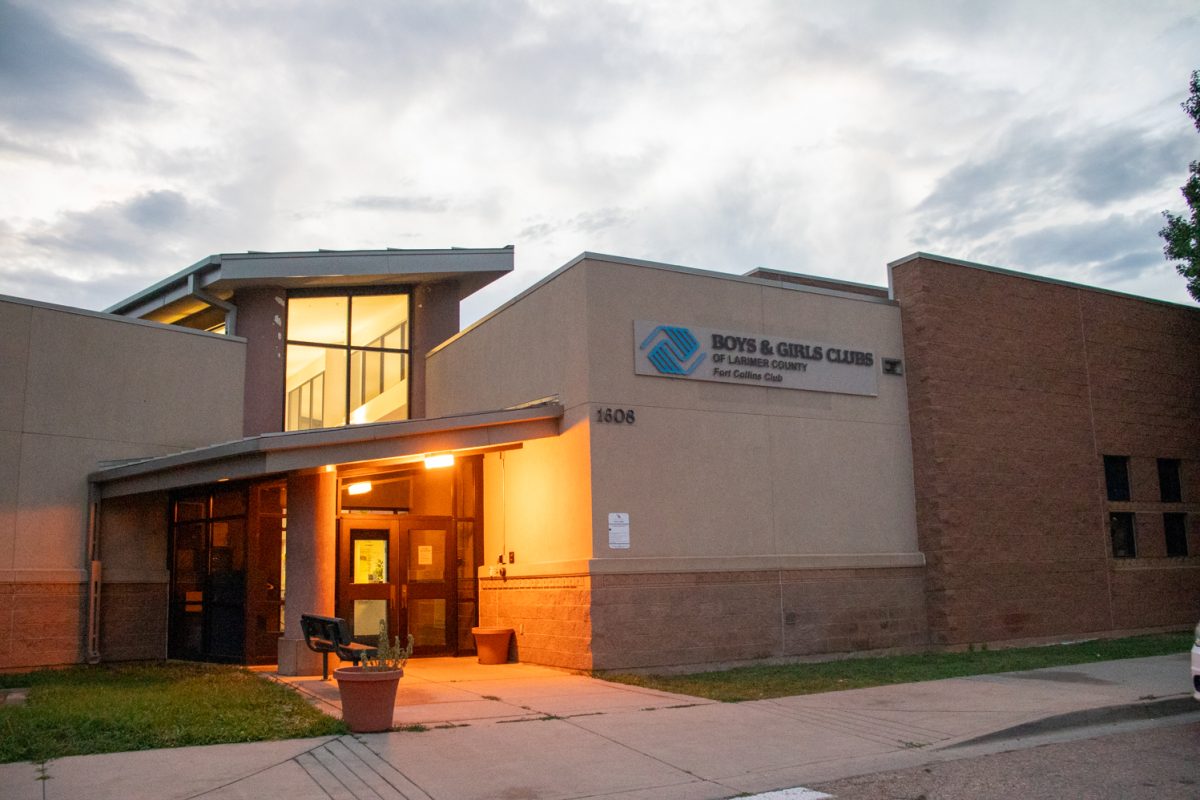 The exterior and parking lot of a building with a white car parked on the right. A sign on the building says "Boys and Girls Club of Larmier County Fort Collins Club.