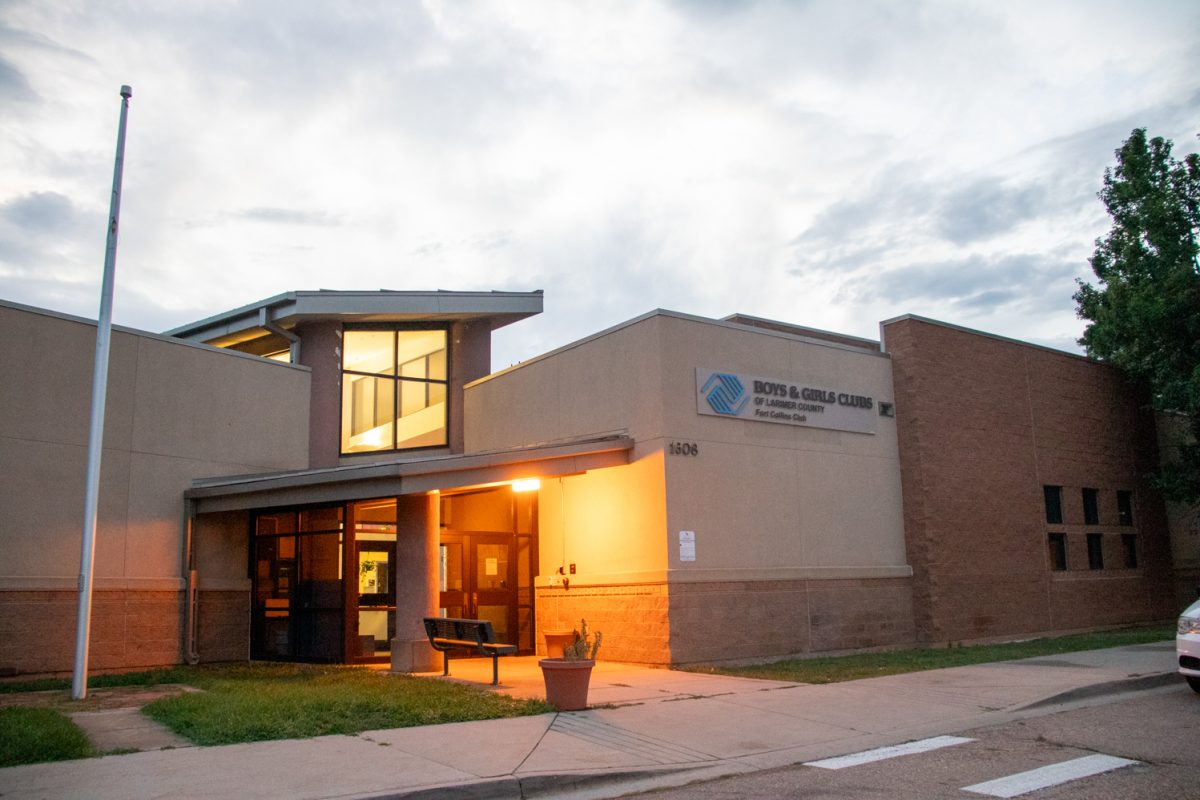 The exterior and parking lot of a building with a white car parked on the right. A sign on the building says "Boys and Girls Club of Larmier County Fort Collins Club.