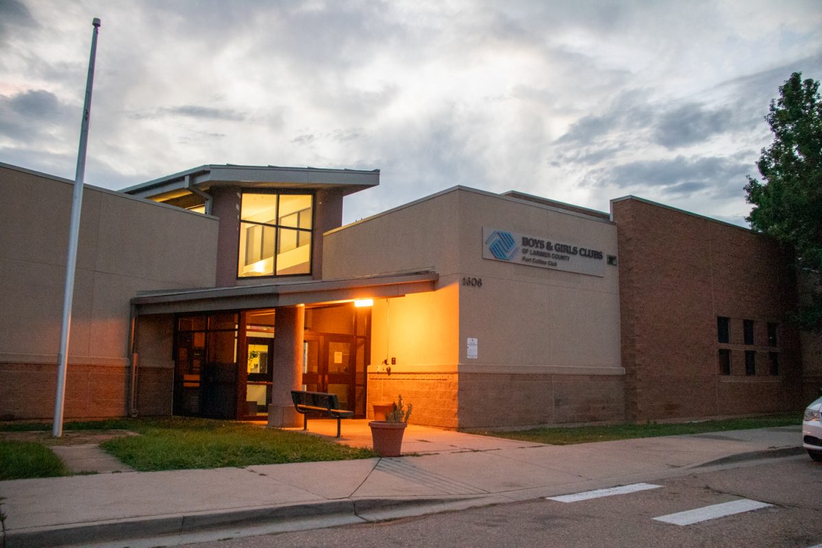 The exterior and parking lot of a building with a white car parked on the right. A sign on the building says "Boys and Girls Club of Larmier County Fort Collins Club.