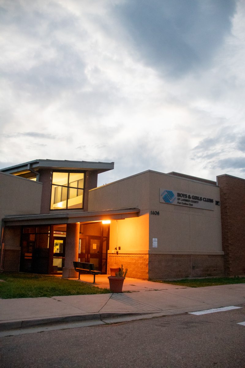 The exterior and parking lot of a building with a white car parked on the right. A sign on the building says "Boys and Girls Club of Larmier County Fort Collins Club.