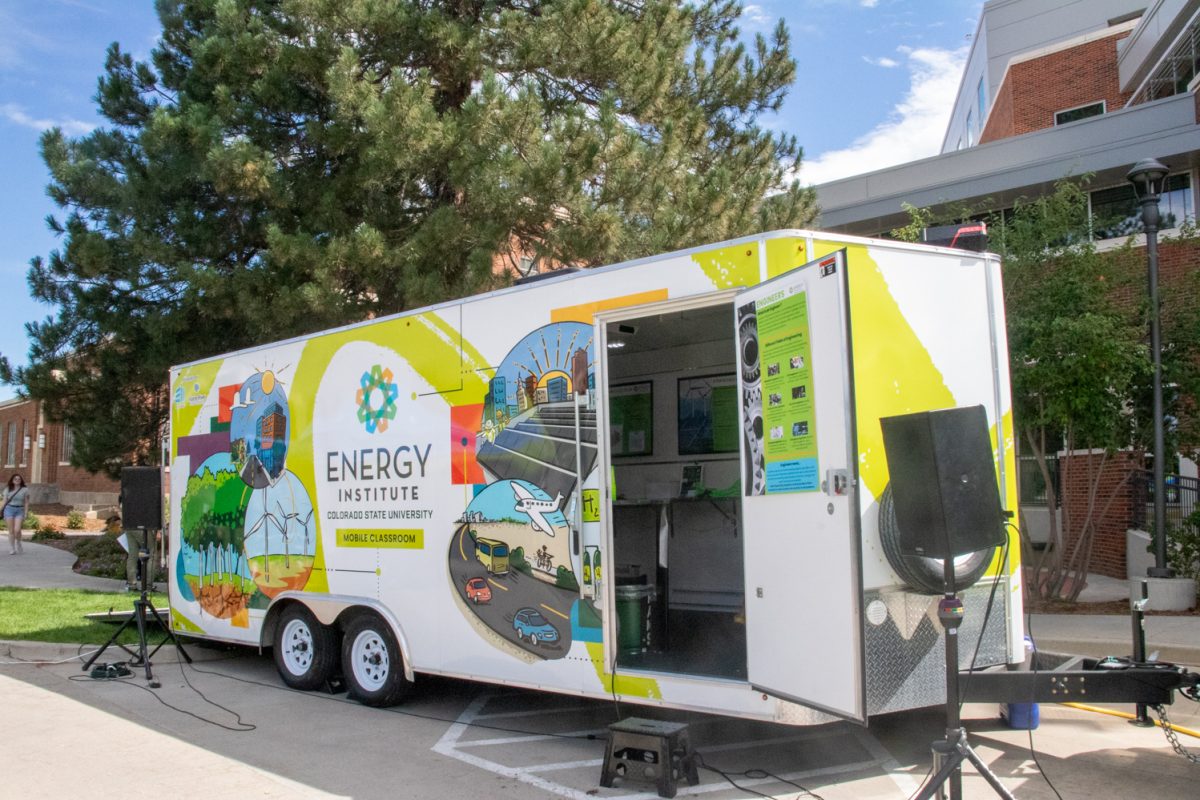 A trailer with colorful energy-related designs on it is parked in front of a building.