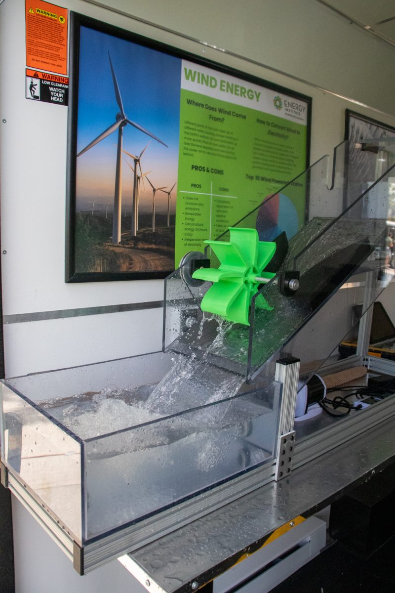 Water is flowing down a tilted plastic container through a green turbine into receptacle.