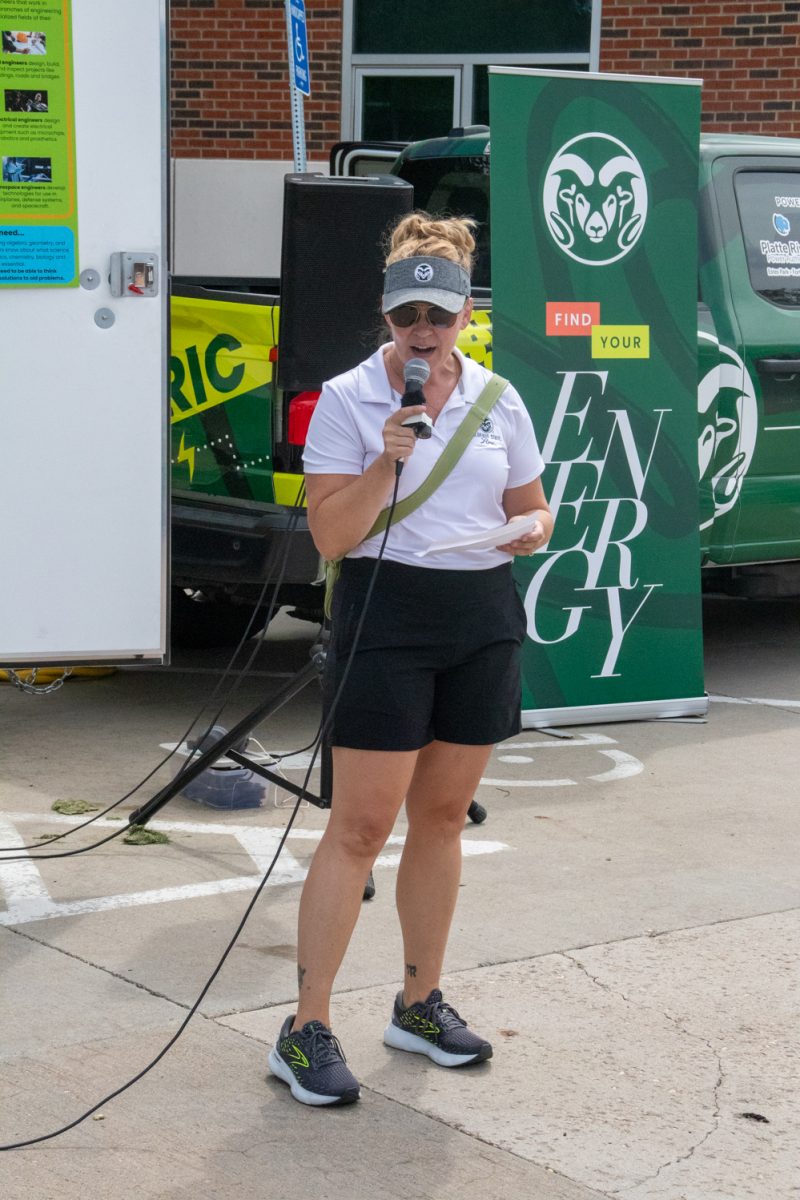 A woman talking into a microphone in front of a truck.