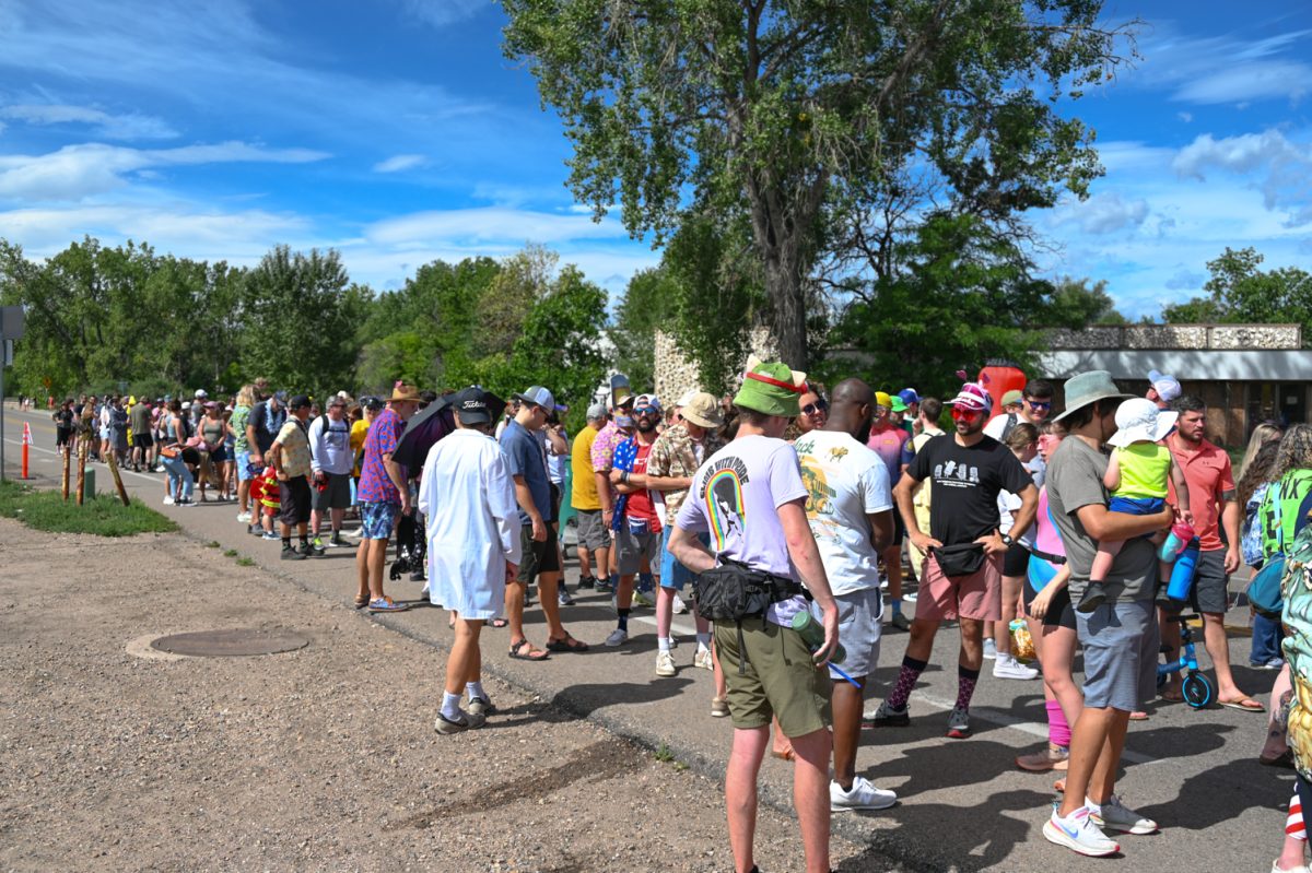 A large line of people dressed in fun costumes outside under a blue sky