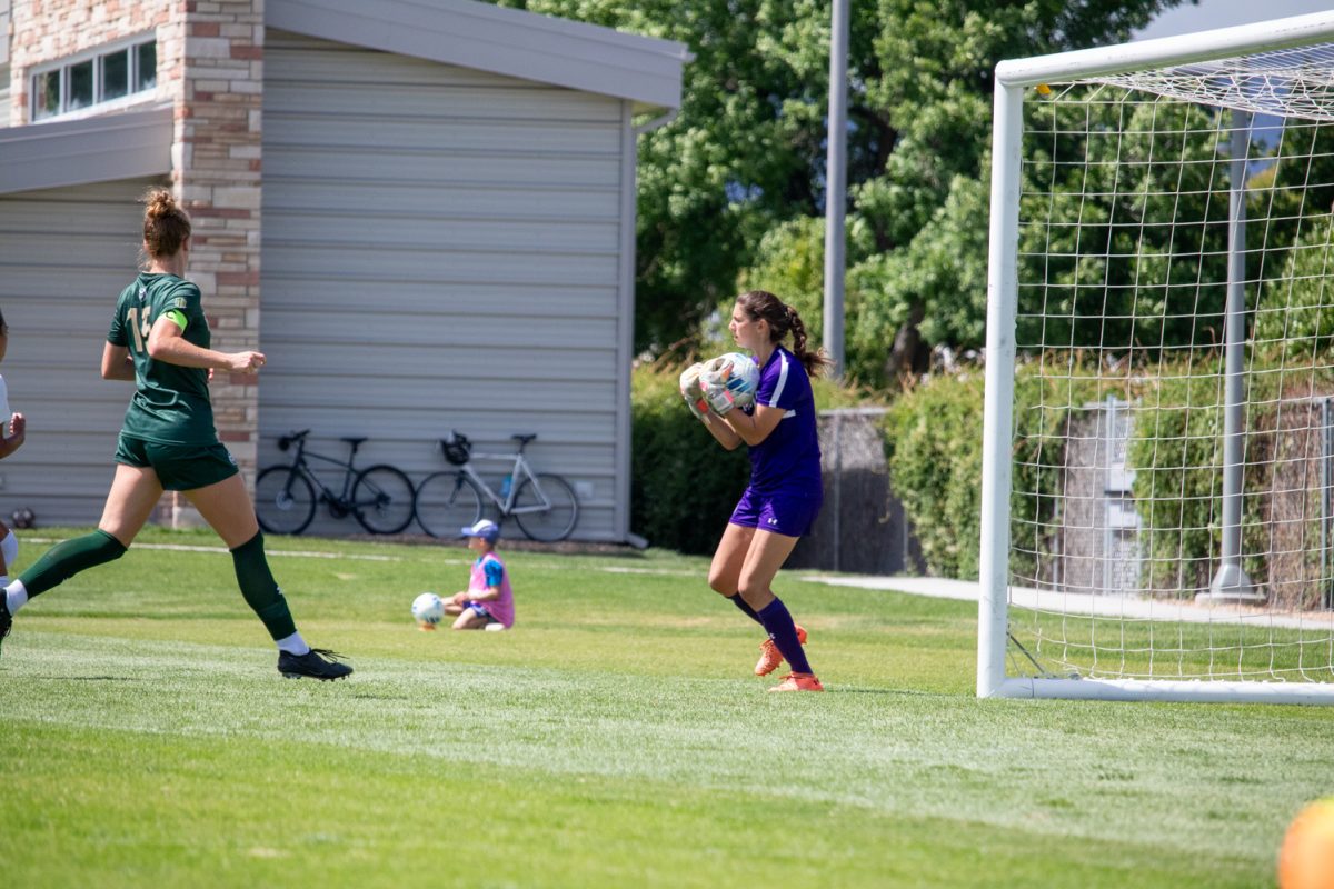 A soccer goaltender picks up the ball.