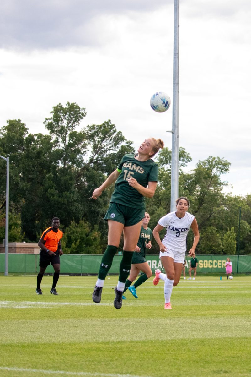 A soccer player jumps into the air to hit the soccer ball with her head.