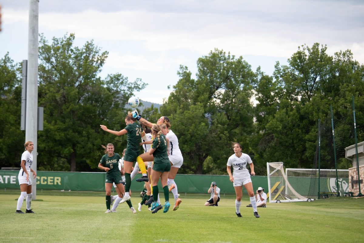 Four soccer players jump to try to get the ball.