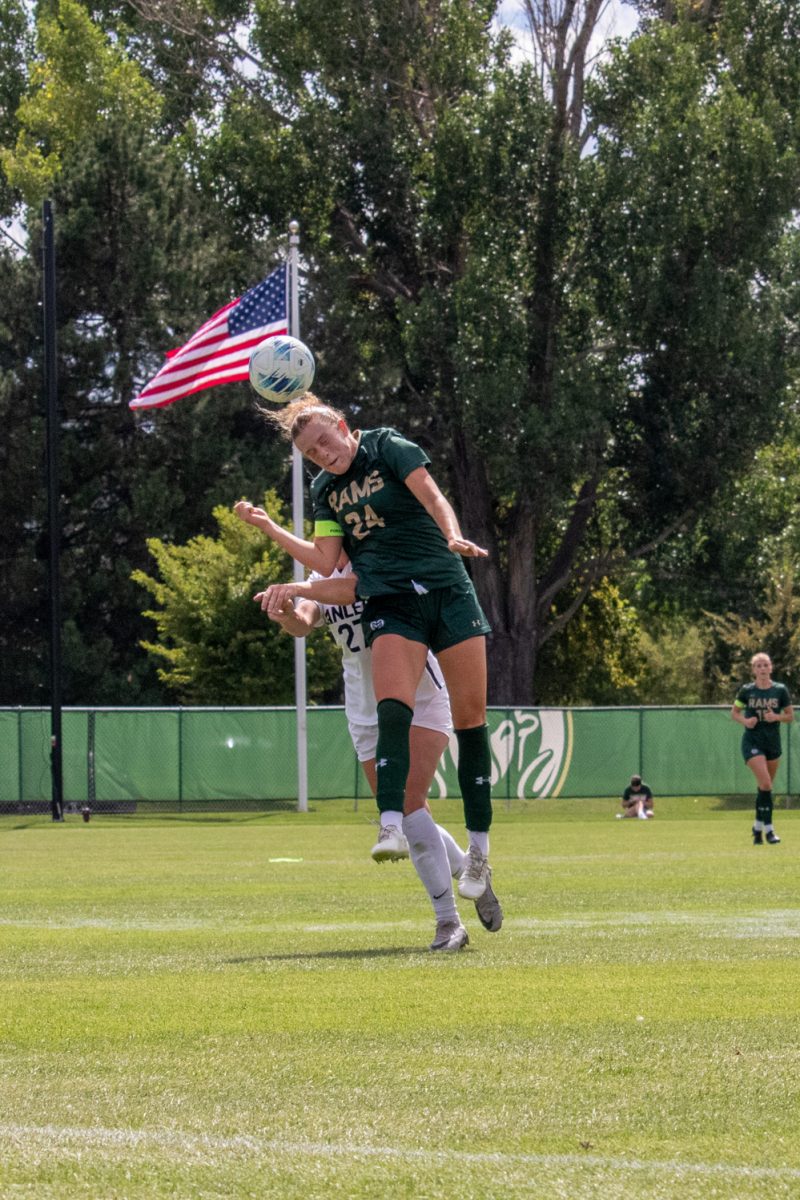 A soccer player jumps into the air to try to hit the ball with her head.