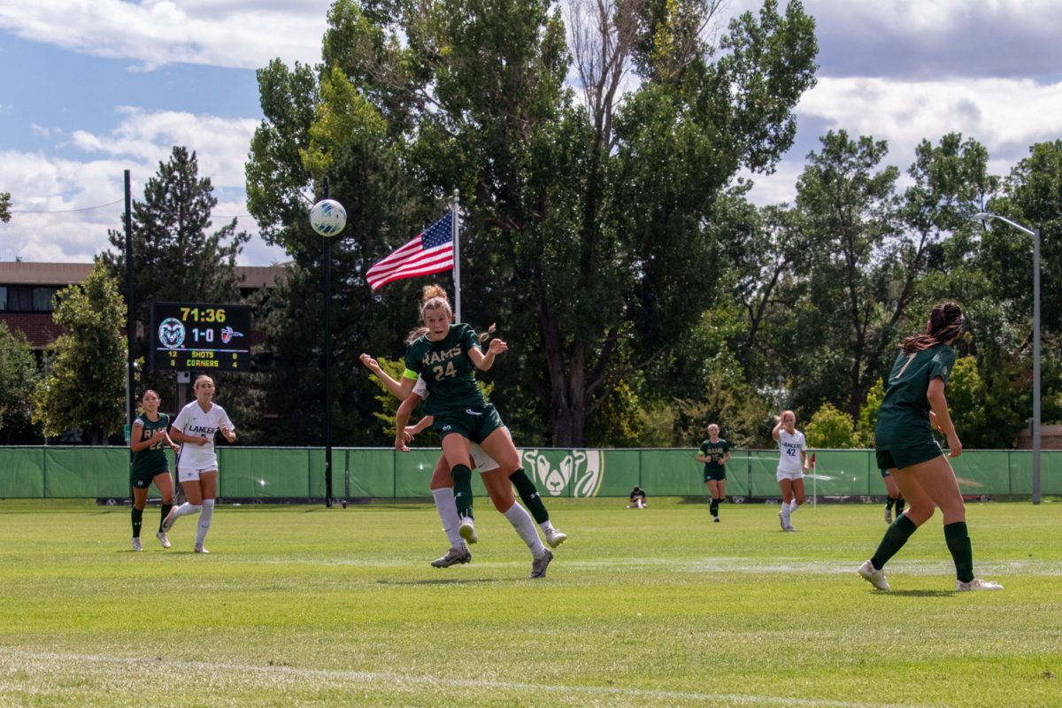 A soccer player jumps into the air to try to hit the ball with her head.