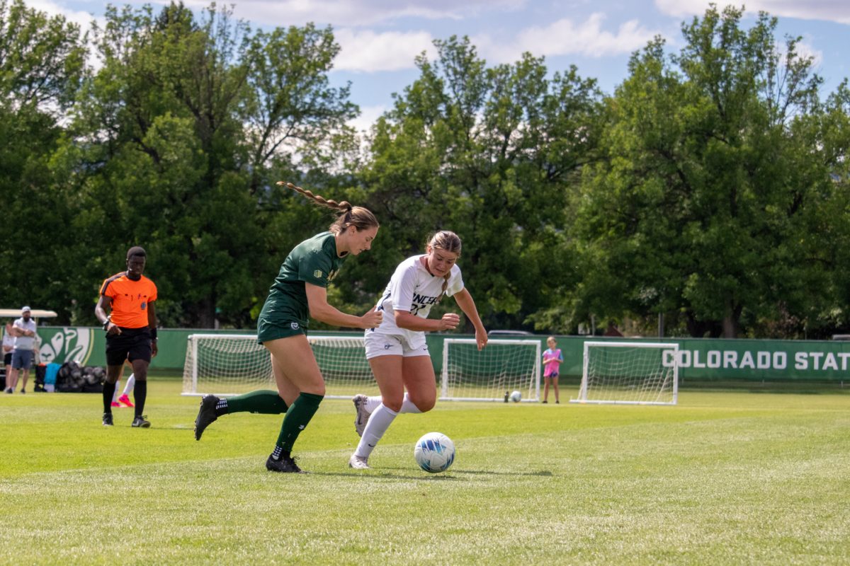 A soccer player from each team run after the ball.