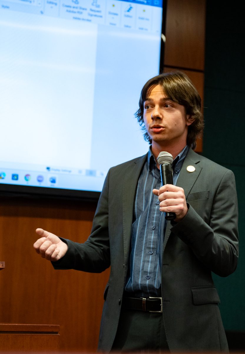 Associated Students of Colorado State University President Nick DeSalvo talks into a microphone and gestures with his free right hand.