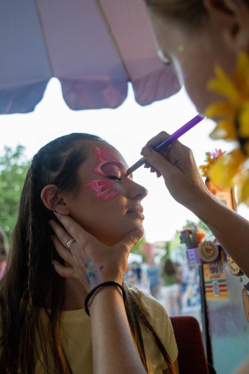 Colorado State University student Hannah Cable gets a bright pink butterfly painted on her face at Ramapalooza. Aug. 16