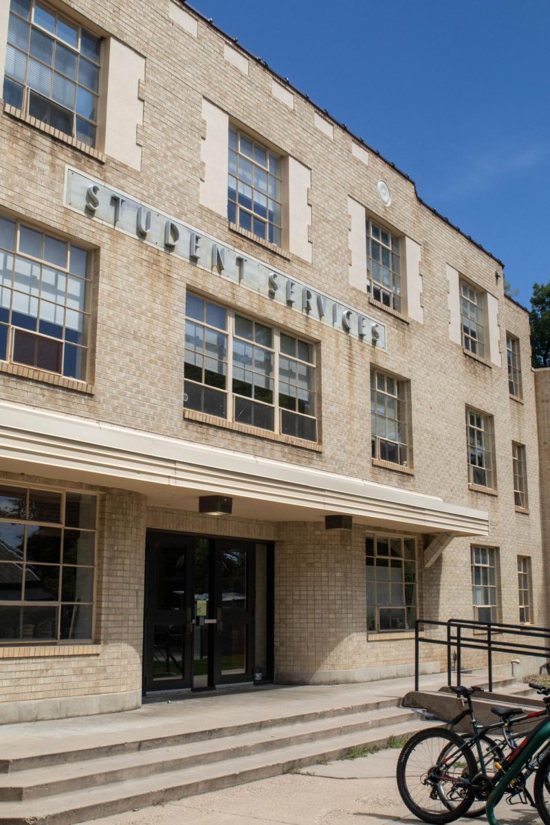 A left-side view of an old brick building with big letters that spell "Student Services"