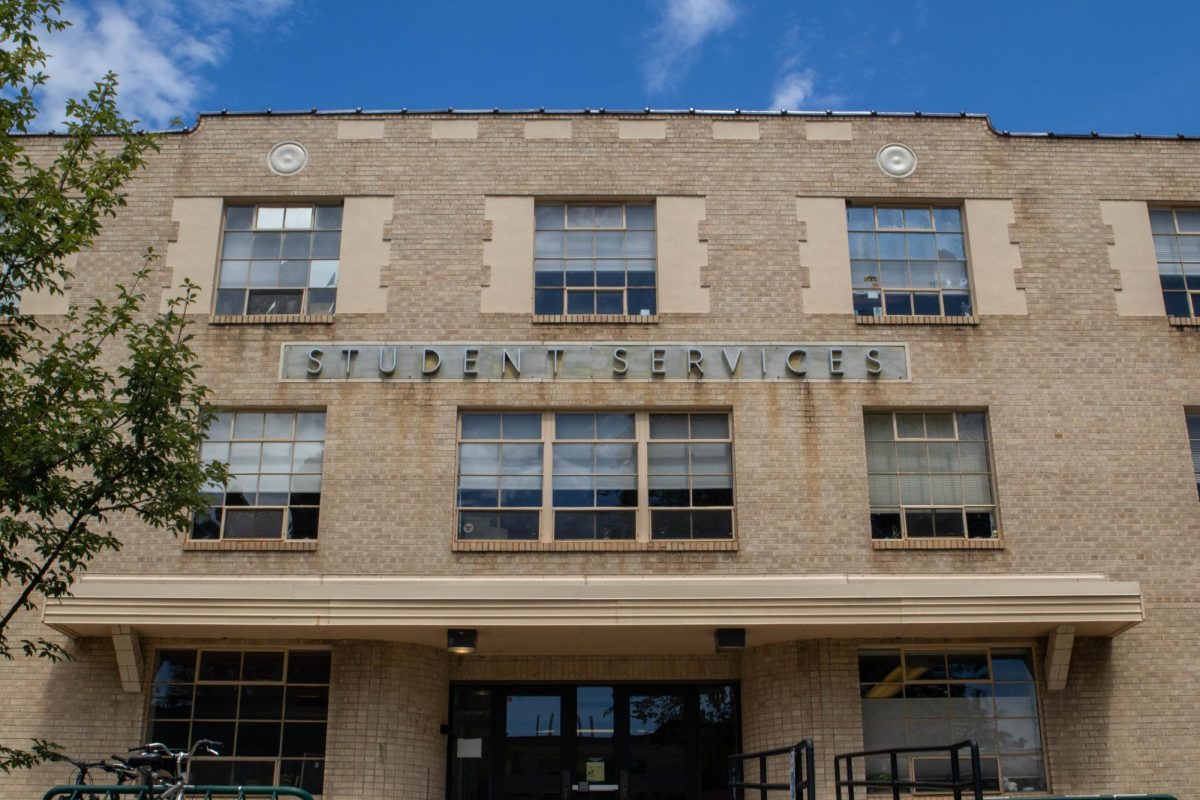 An old three sotry brick building is seen with Student Services spelled out in big letters above the entrance