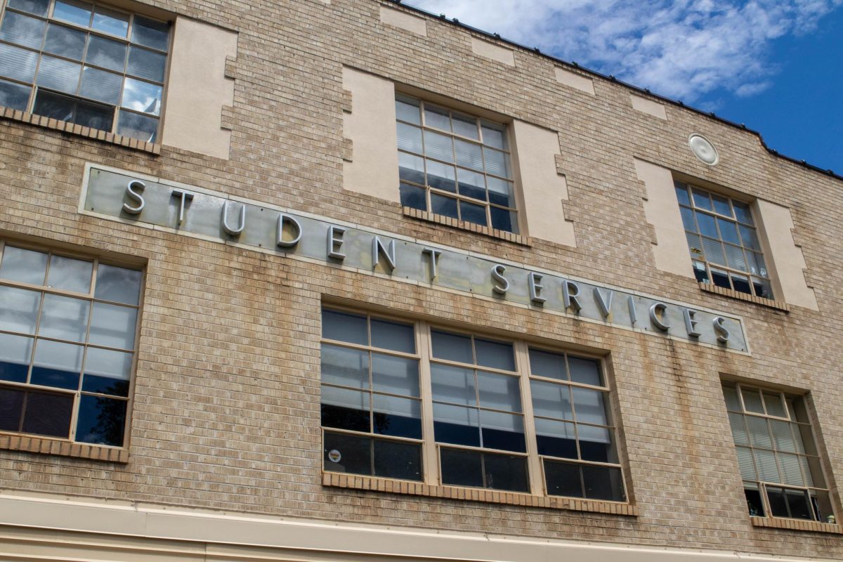 The front of an old brick building with big letters spelling Student Services.