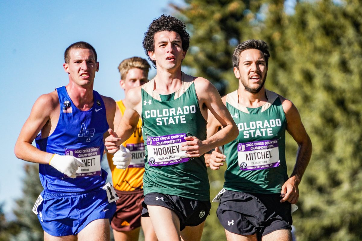 This is an image of four men running a race. Two are in green jerseys and the other is in a blue jersey the fourth is in a yellow jersey.