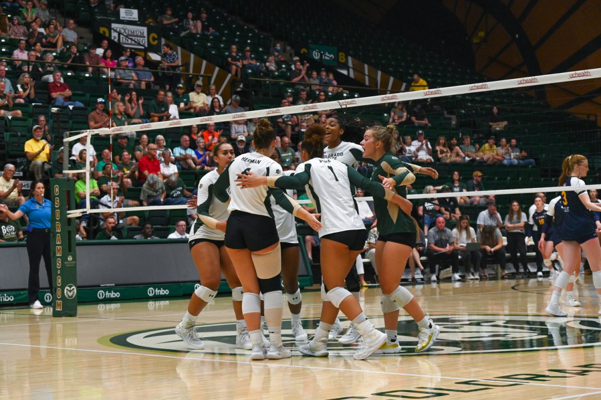 a group dressed in green and white long sleeve uniforms with tight black shorts huddle together on the court