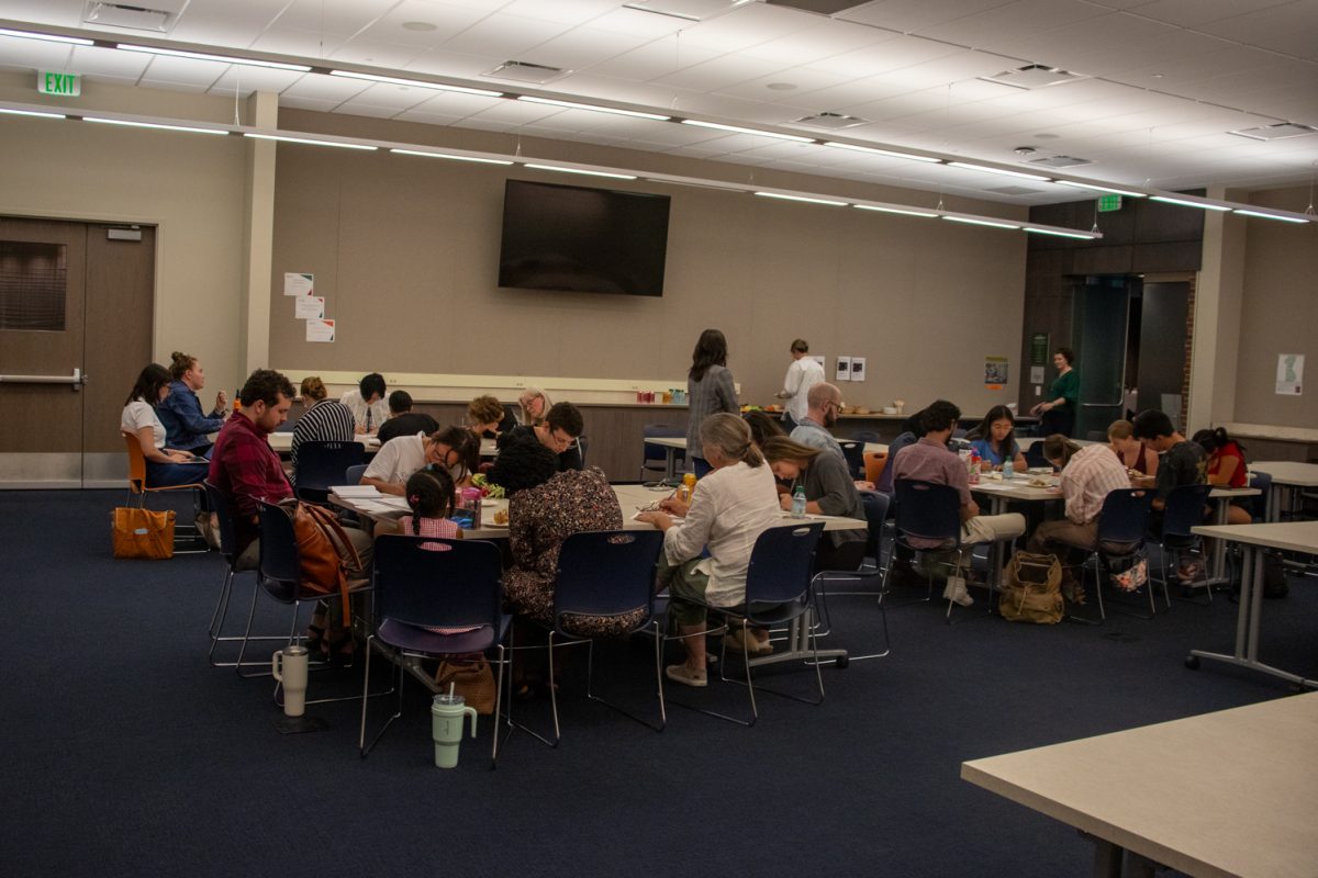 A group of people sit at tables in groups of about 8.