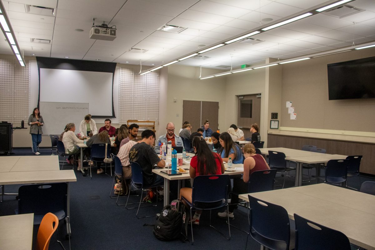 A group of people sit at tables in groups of about 8.