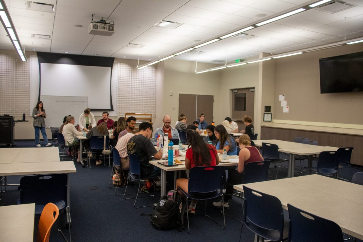 A group of people sit at tables in groups of about 8.