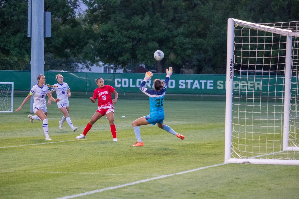 A goaltender deflects a ball on a soccer field.